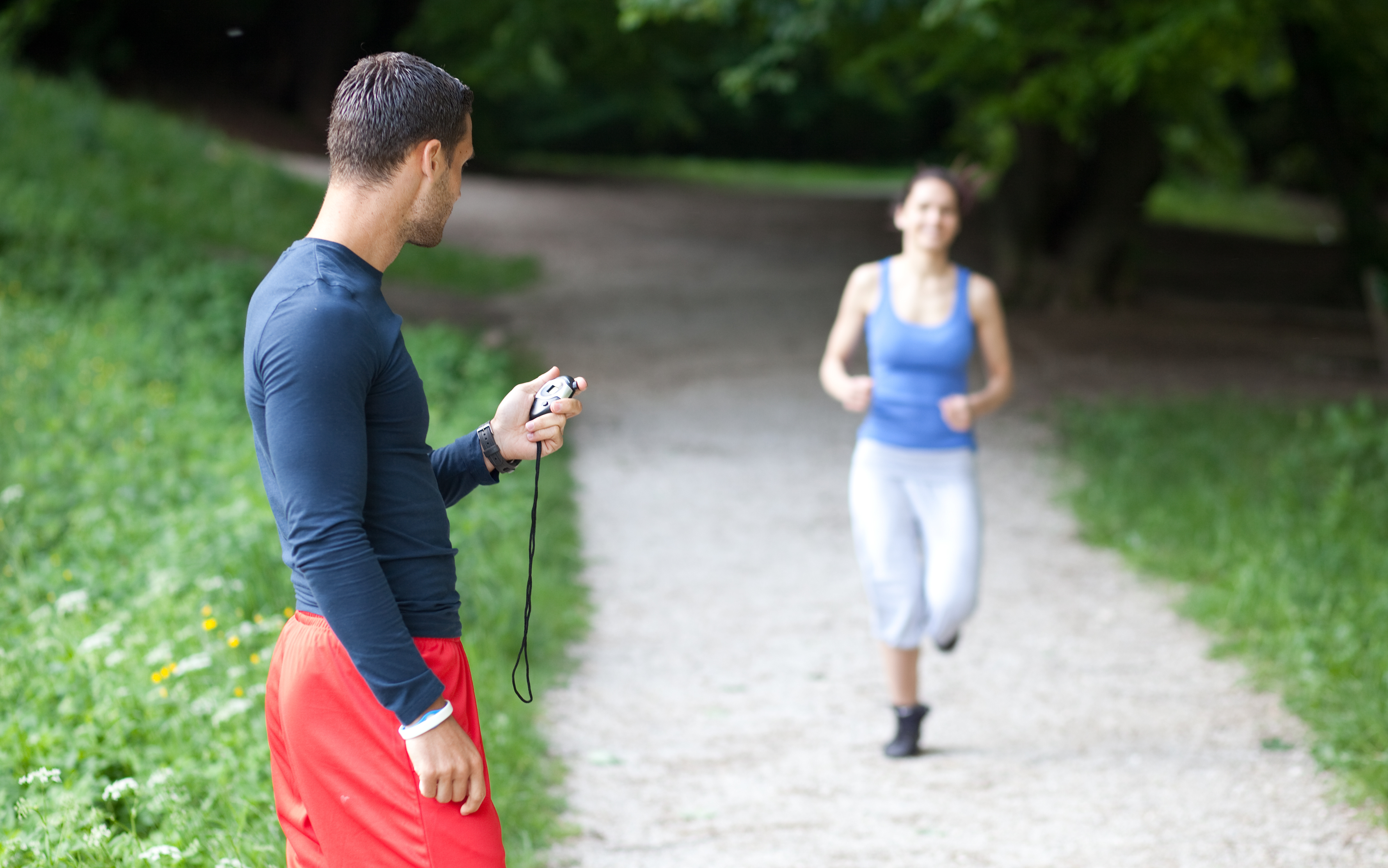 Personal trainer timing a female runner. Selective focus.