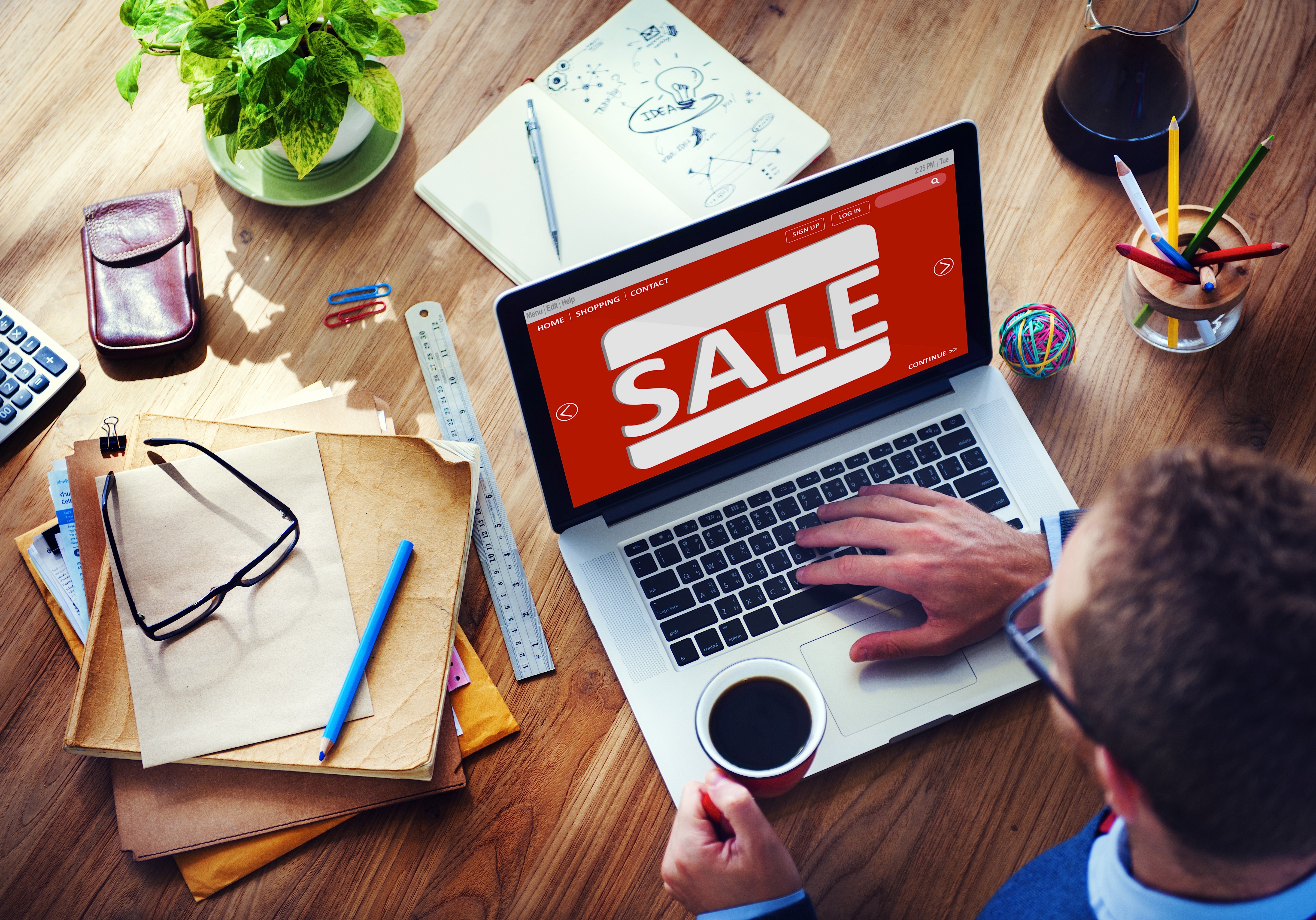 discount-real-estate Man working on computer with sale sign on it and coffee in hand.