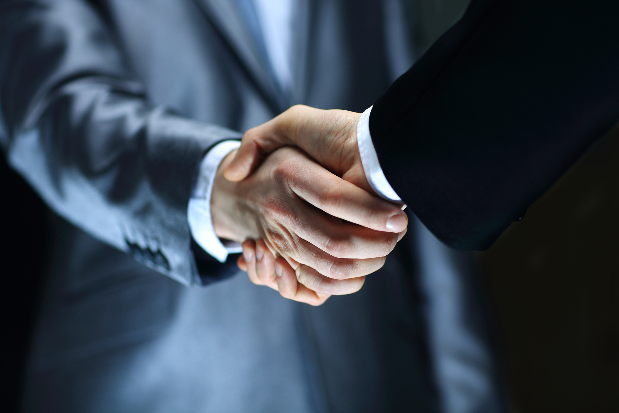 Handshake – Hand holding on black background